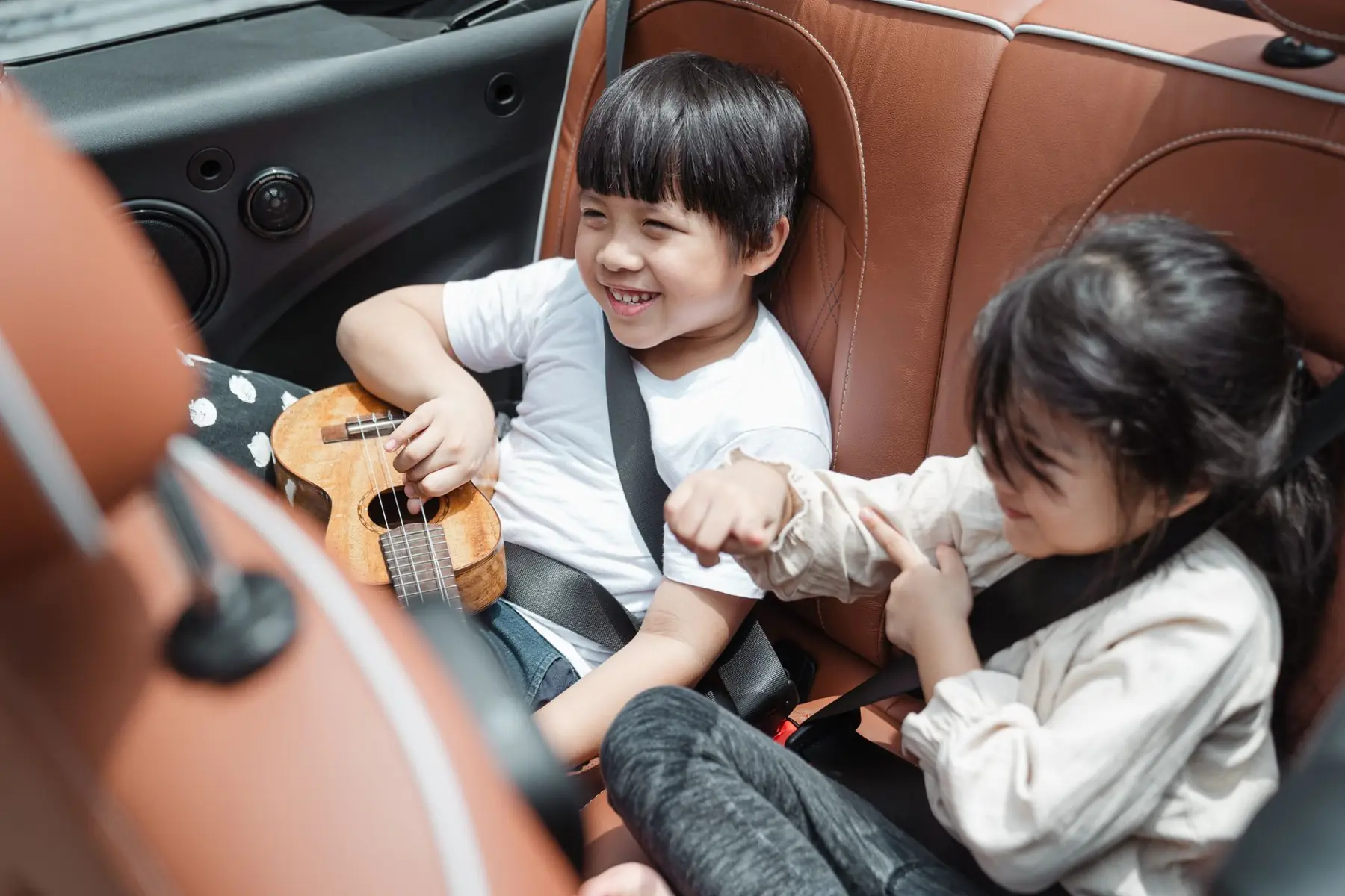 Dos chicos sonríen sentados en el asiento de atrás de un auto