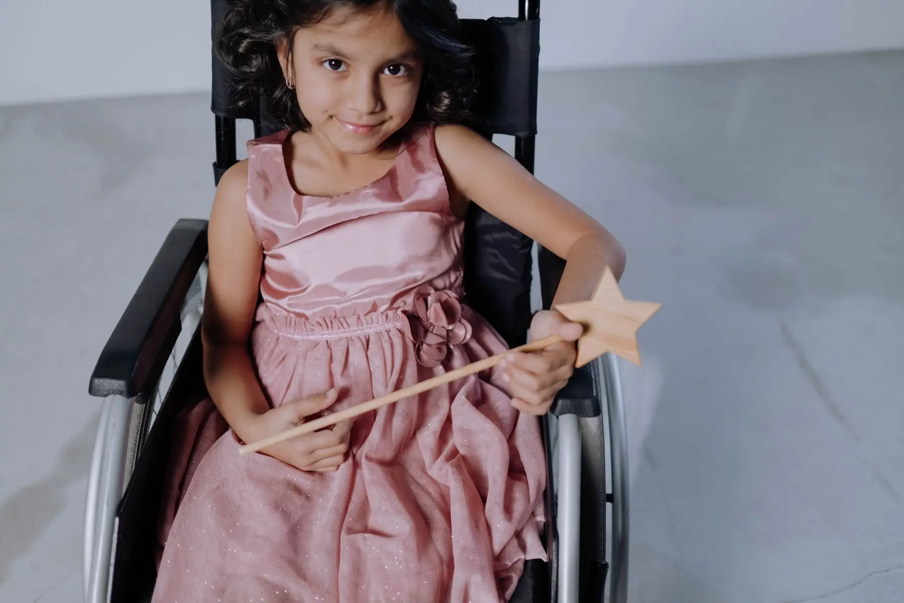 Una nena sonríe sentada en su silla de ruedas